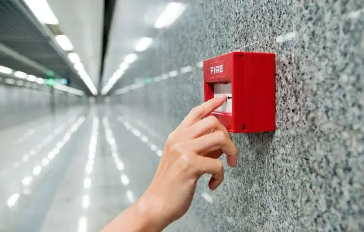 Image of a hand with fingers pushing a fire alarm button